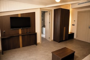 Una sala de estar moderna con un televisor de pantalla plana, un mueble de madera para equipos electrónicos, un armario de madera oscura y una pequeña mesa de madera.