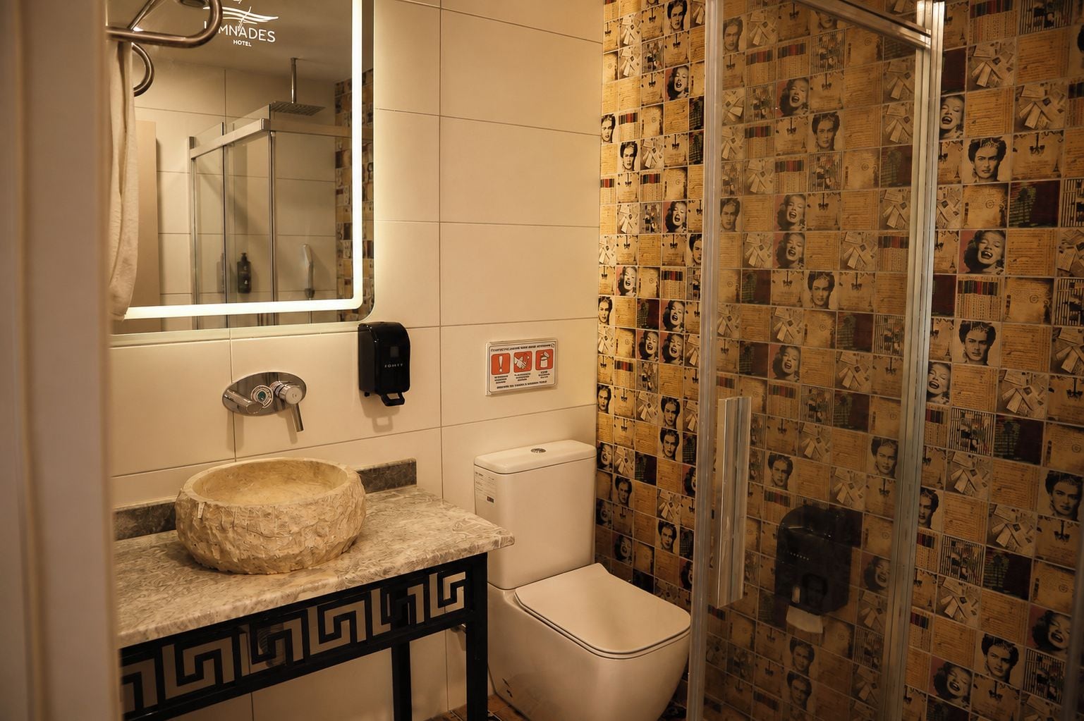 A bathroom with a stone sink, a mirror, a toilet, and a shower.