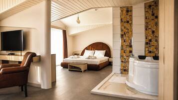 Una habitación de hotel con una cama, televisión, sillón y bañera.