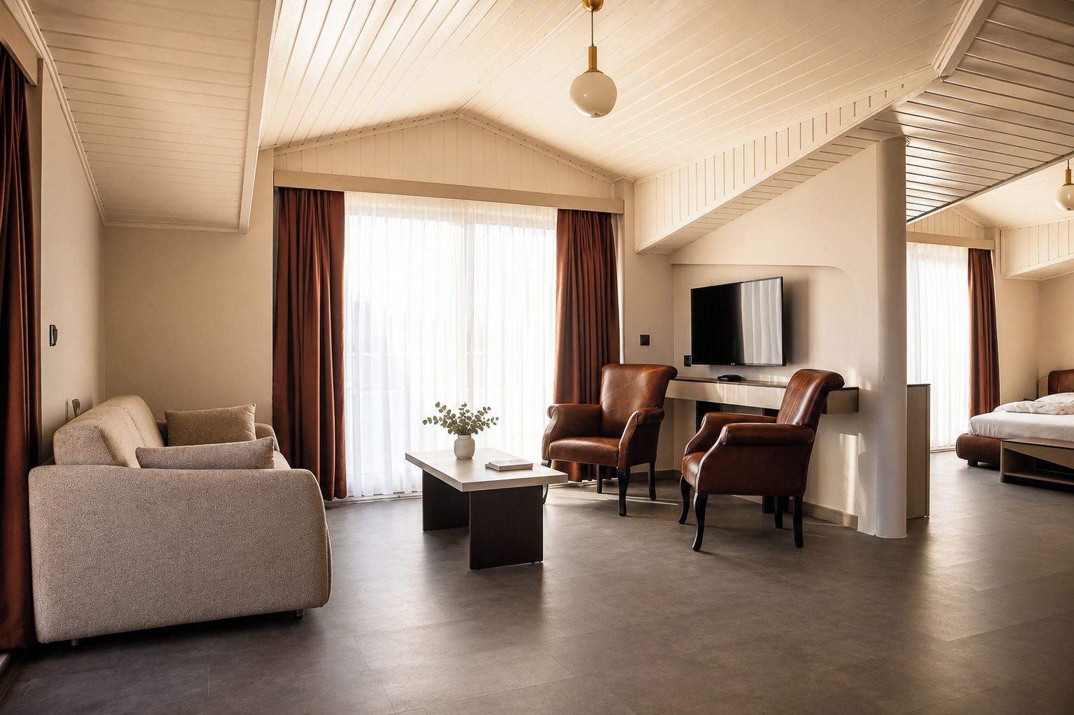 Ein modernes Hotelzimmer mit einer Couch, Sesseln, einem Flachbildfernseher und einem Bett.