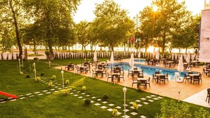 Zona de piscina exterior con diversas opciones de descanso y exhibición de banderas.