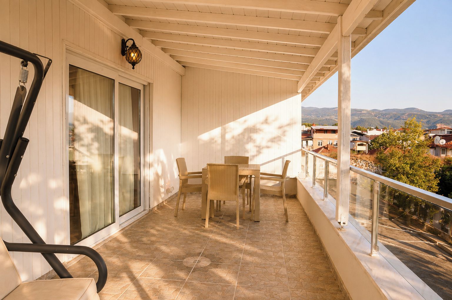 A balcony with a table and chairs, a glass door, and a view of the surrounding landscape.
