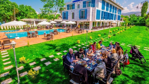 Un hotel con piscina, zona de comedor al aire libre y un edificio grande con contraventanas azules.