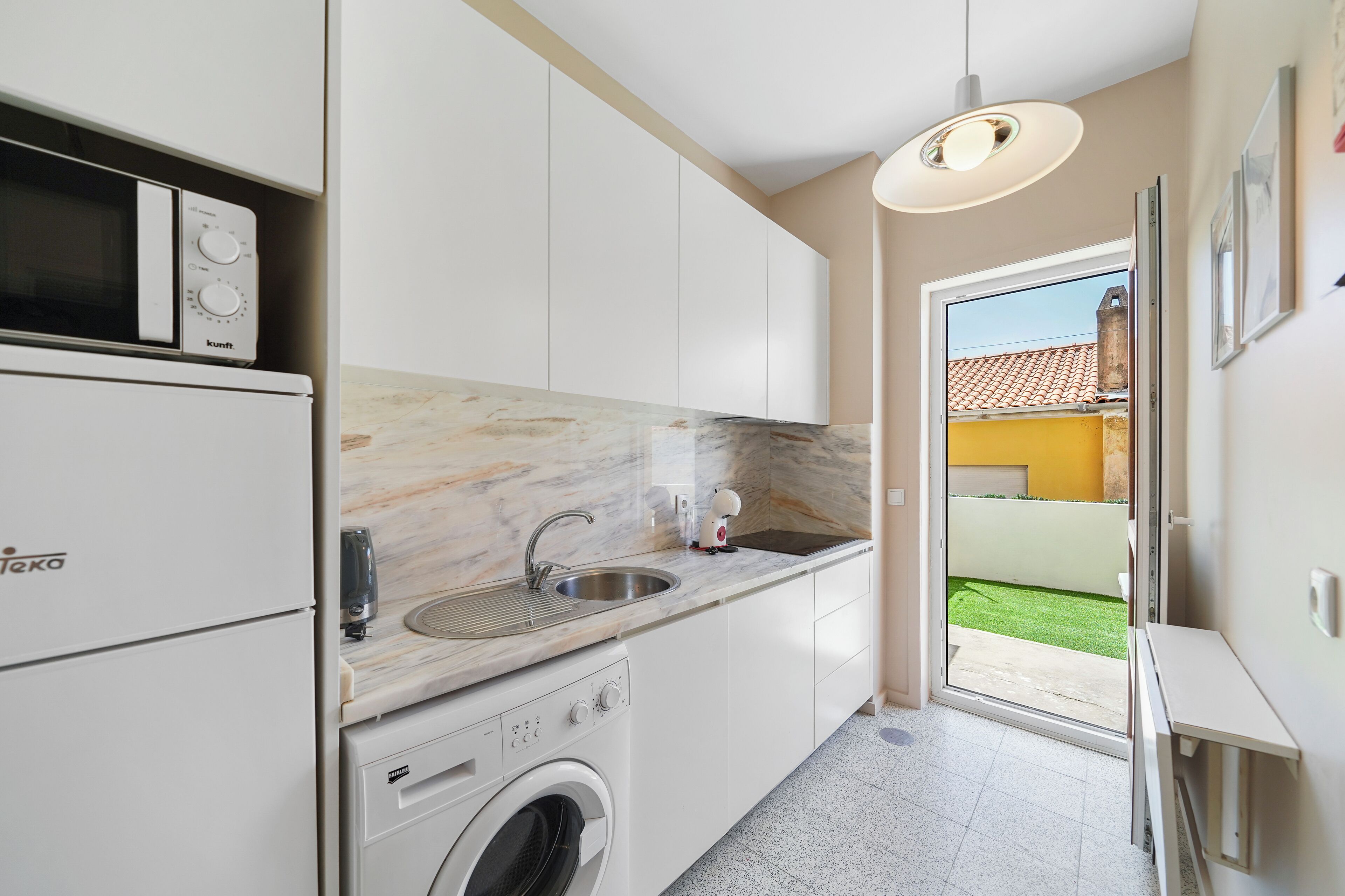 A compact kitchen with a built-in washing machine, a sink, and a microwave.