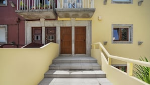 A staircase leading to a building entrance with a yellow facade, a small window, and a balcony with railings. - Apartments Luiz I Bridge (Vila Nova de Gaia)