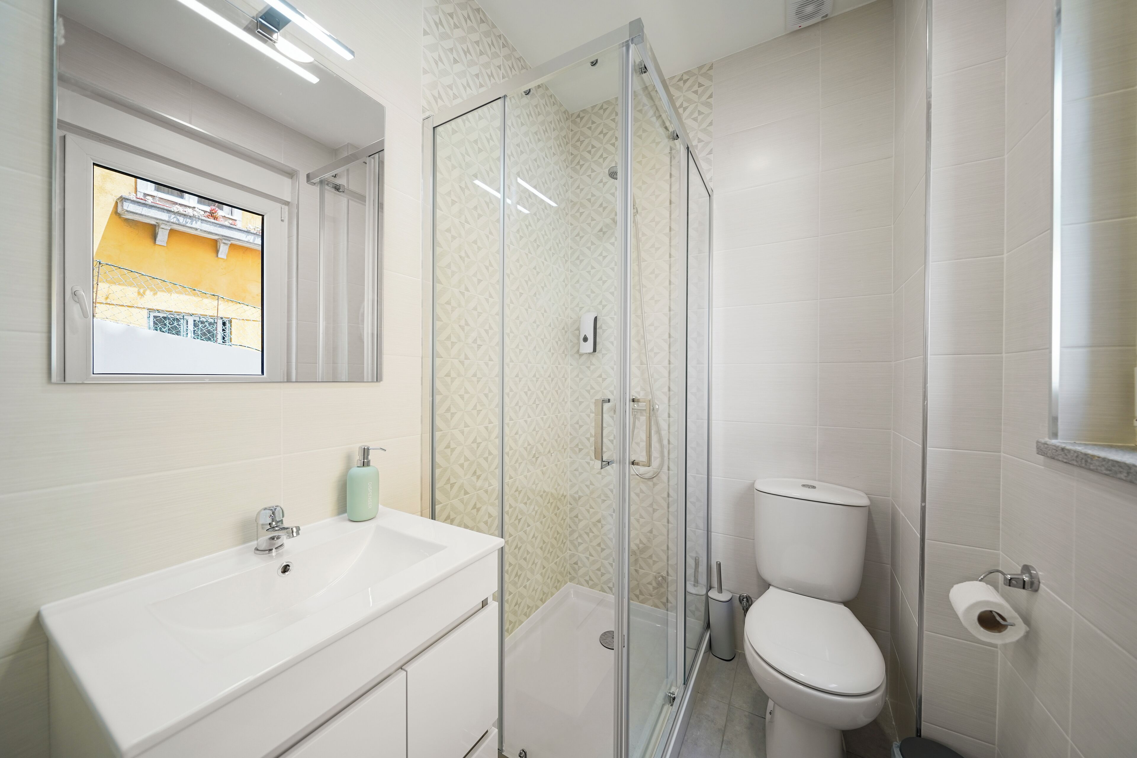 A modern bathroom with a glass-enclosed shower, a white sink, and a toilet.