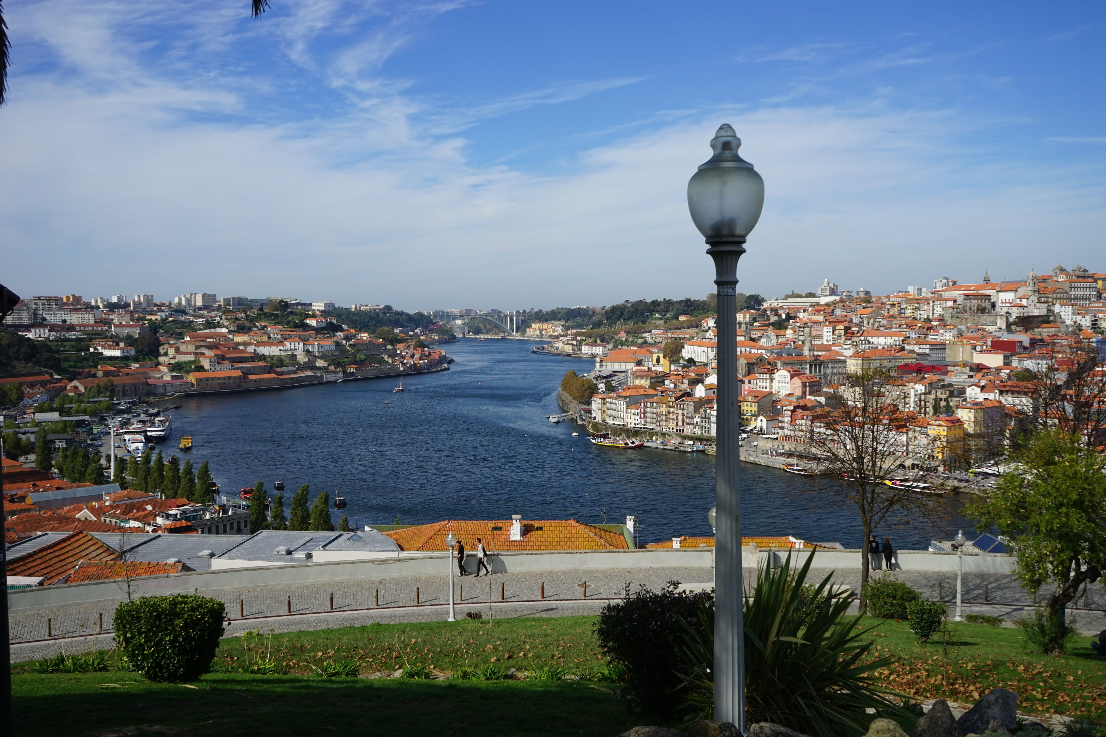 A river with buildings on both sides, a bridge in the distance, and a lamp post in the foreground.
