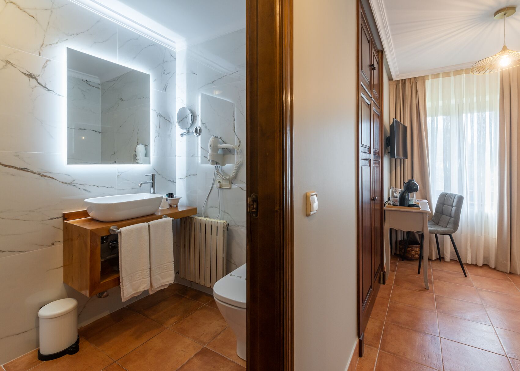 A modern bathroom with a marble sink, a mirror, a hairdryer, and a toilet.