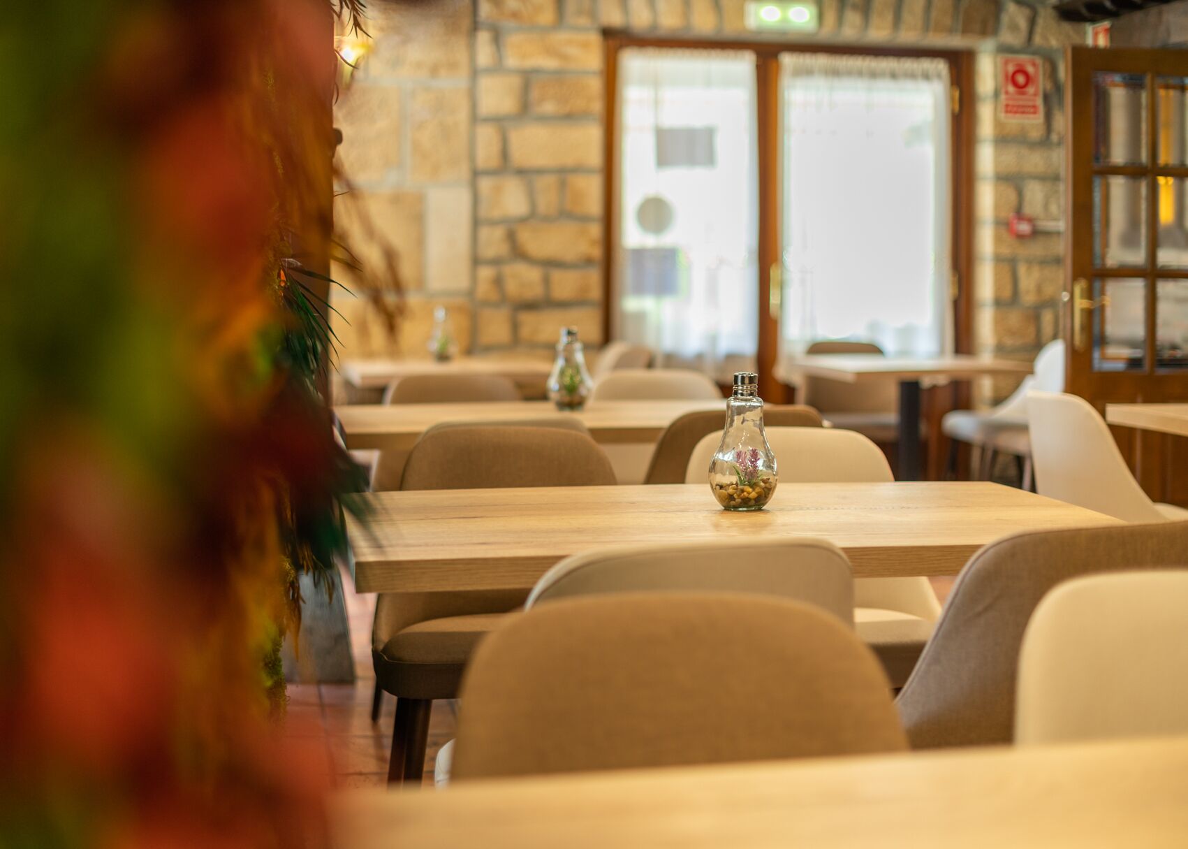 A restaurant interior with stone walls, wooden tables, and chairs.