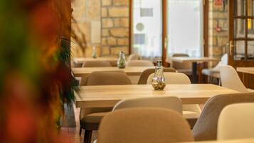 A restaurant interior with stone walls, wooden tables, and chairs.