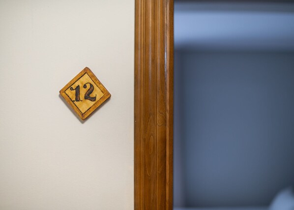 A wooden door frame with a number plaque on a white wall.