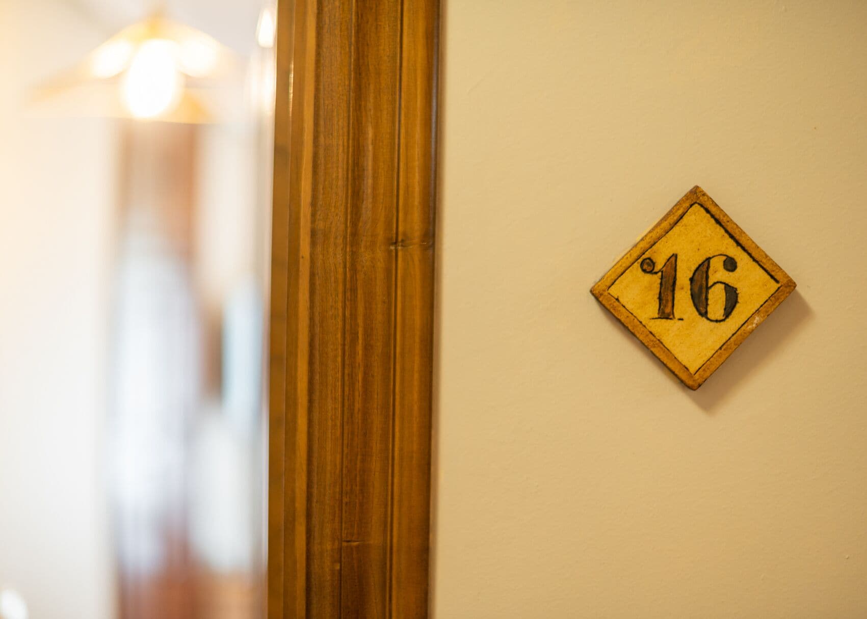 A wooden door with a number plaque on the wall.