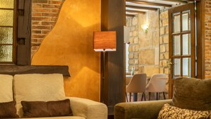 A cozy living room with a brick wall, a sofa, a coffee table, and a lamp. - Logis Hotel Restaurante La Casa de Juansabeli (Cabrales)