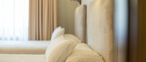 Una habitación de hotel con una cama bien hecha, una lámpara de pared y un ventanal con cortinas.