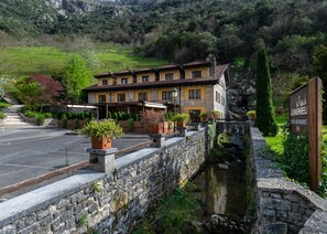 Un edificio de piedra tradicional con un patio, un pequeño canal y un letrero que indica que es un hotel y restaurante.