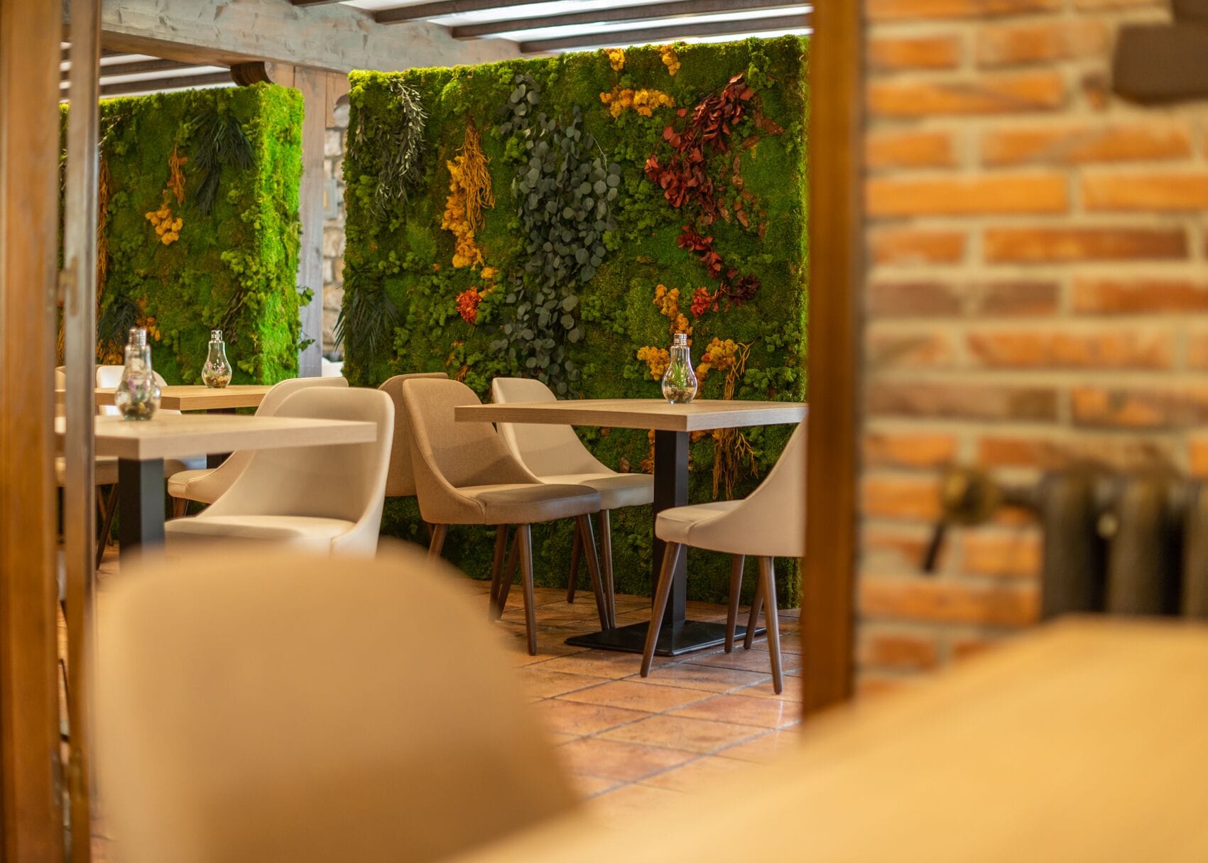 A restaurant interior with a brick wall and a green wall adorned with plants and flowers.