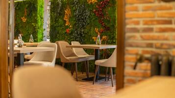 A restaurant interior with a brick wall and a green wall adorned with plants and flowers.