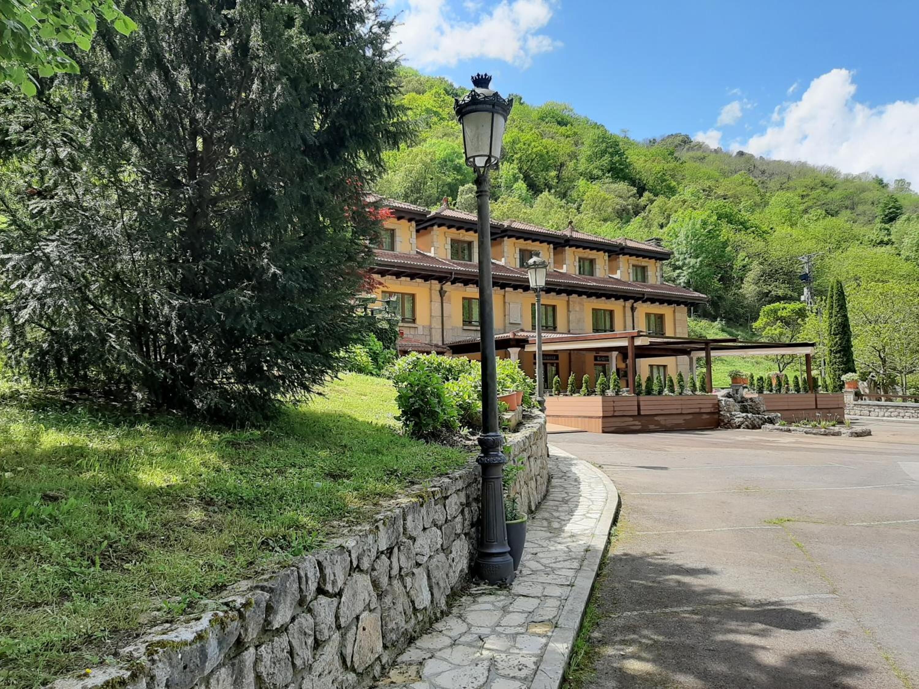 Un edificio con un muro de piedra, un farol y una zona pavimentada.