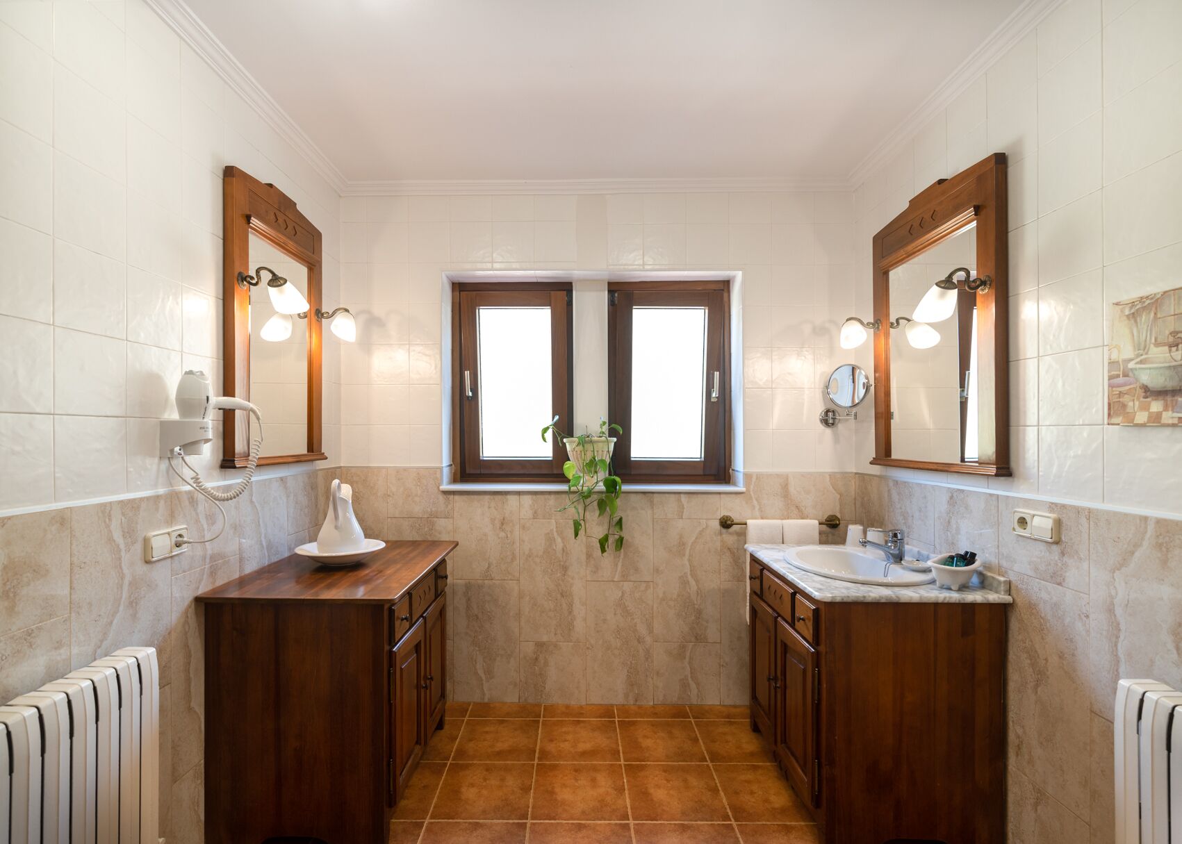 Een badkamer met twee wastafels, een raam en een spiegel.