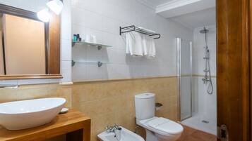 A modern bathroom with a large sink, toilet, bidet, and shower.