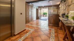 A hallway with a tiled floor, a reception desk, and a stone wall. - Logis Hotel Restaurante La Casa de Juansabeli (Cabrales)