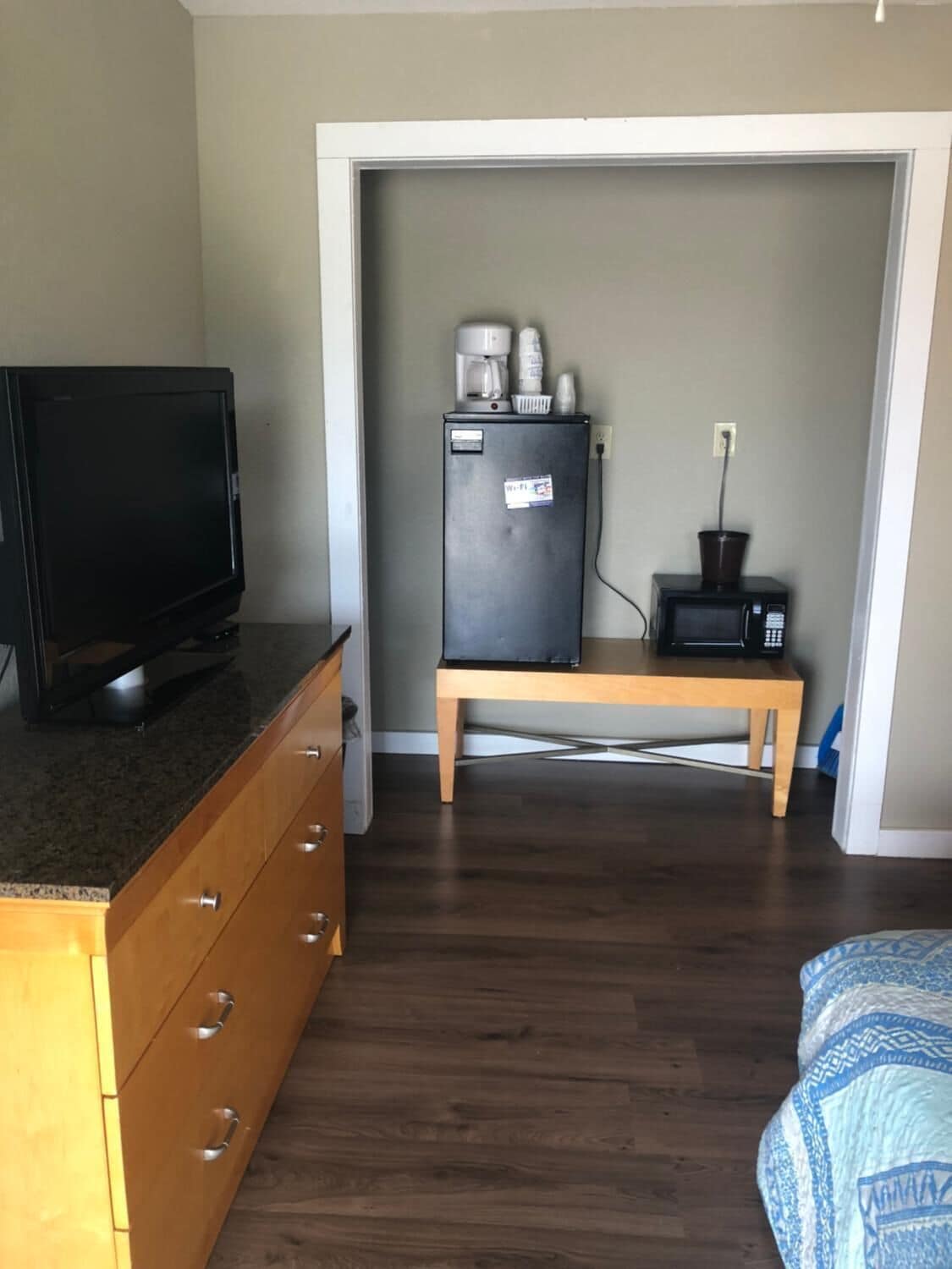 A compact room with a wooden dresser, a television, a refrigerator, and a microwave.