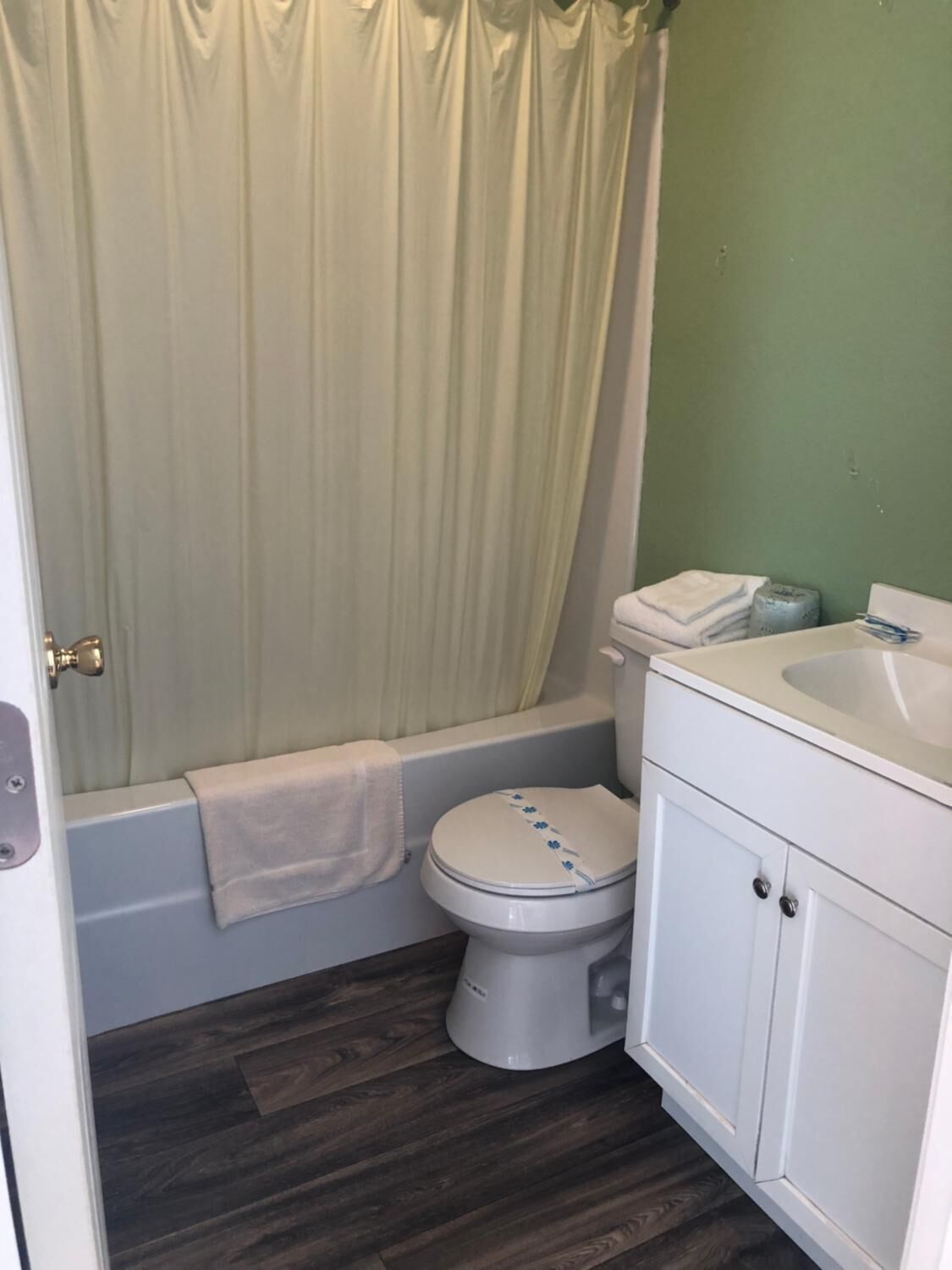 Une salle de bain équipée de toilettes, d’une baignoire, d’un lavabo et d’un rideau de douche.