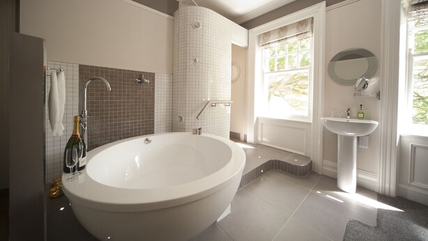 A modern bathroom with a freestanding bathtub, a vanity with a mirror, and a window providing natural light.