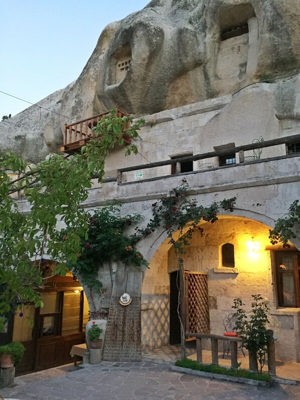 A rustic building with a stone facade, wooden balcony, and arched doorways.