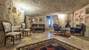A cozy, stone-walled room with a fireplace, plush seating, and a checkered floor.