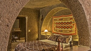 A cozy room with a bed, a lamp, a decorative rug, and a small table with a copper jug and figurines.