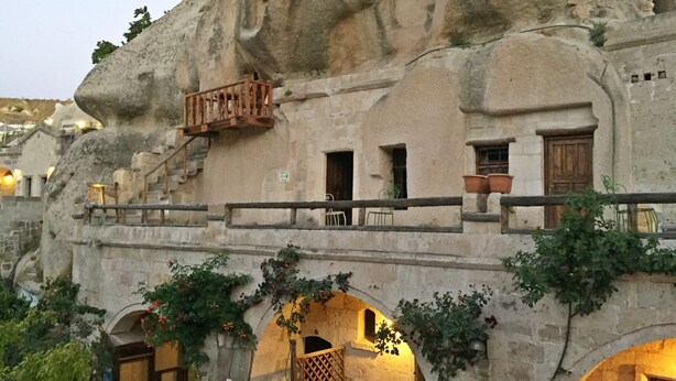 A building with unique rock-like architecture, featuring balconies and arched doorways.