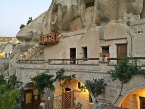 A building with unique rock-like architecture, featuring balconies and arched doorways. - Antique Terrace Suites (Nevsehir)