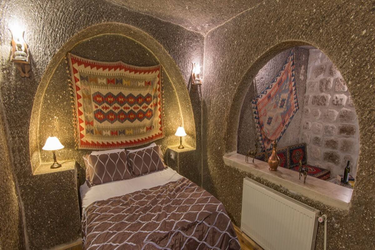 Un dormitorio acogedor con cama, dos lámparas de pared, un radiador y un tapete estampado.