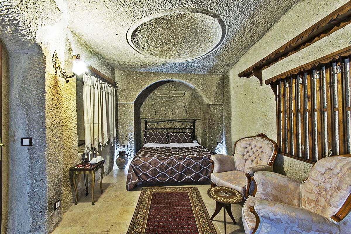Una habitación con una cama, dos sillones, una mesita y un tapete decorativo.