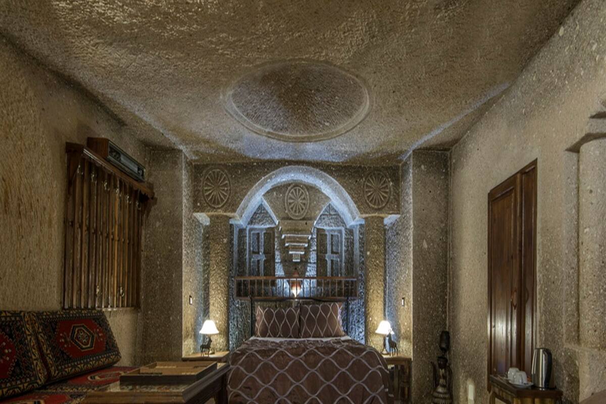 Una habitación tradicional con cama, sofá, mesa y lámpara.