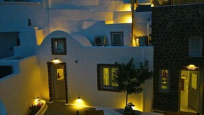 A modern building with a unique architectural design, featuring multiple levels and a courtyard with seating areas. - Fertimo Suites (Santorini)