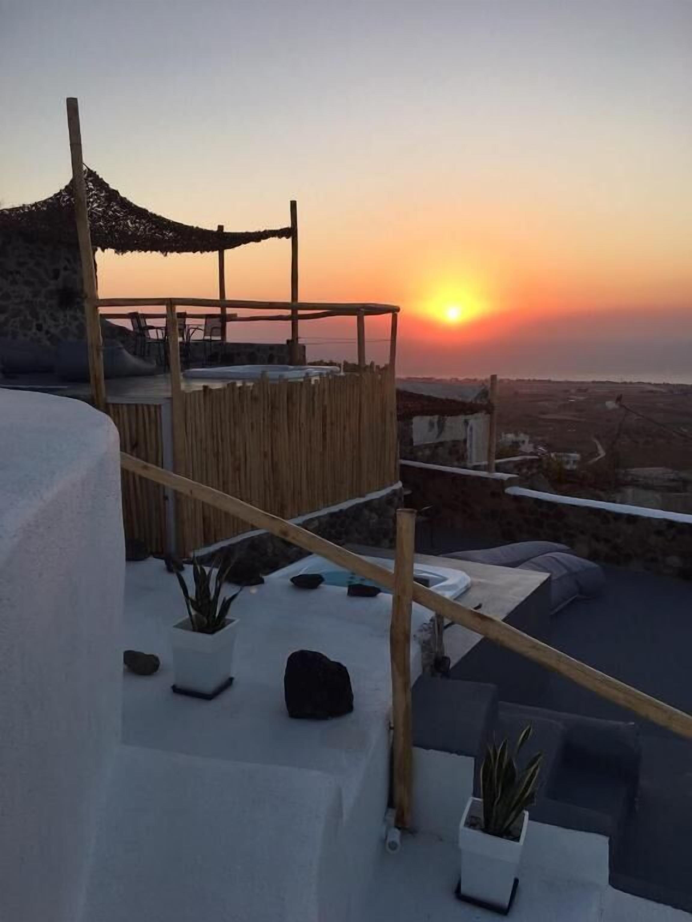 Une terrasse sur le toit offrant une vue sur le coucher de soleil, avec des murs blancs et des plantes en pot.