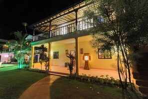 A two-story building with a covered balcony and a well-lit entrance. - Amour Resort (Vagator)