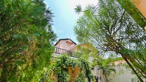 A house with a balcony, surrounded by lush greenery and a well-maintained lawn. - Amour Resort (Vagator)