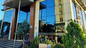 Un hôtel moderne à la façade incurvée, doté de nombreux balcons et offrant une vue sur un ciel dégagé.