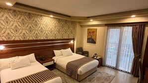 Une chambre d’hôtel avec deux lits, une grande fenêtre avec des rideaux, un tableau au mur et une tête de lit en bois.