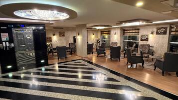 A hotel lobby with a black and white striped floor, a reception desk, and several seating areas.