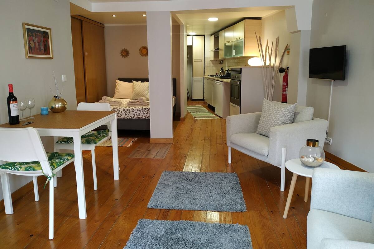 A modern apartment with a dining area, a living room, a kitchen, and a bedroom.