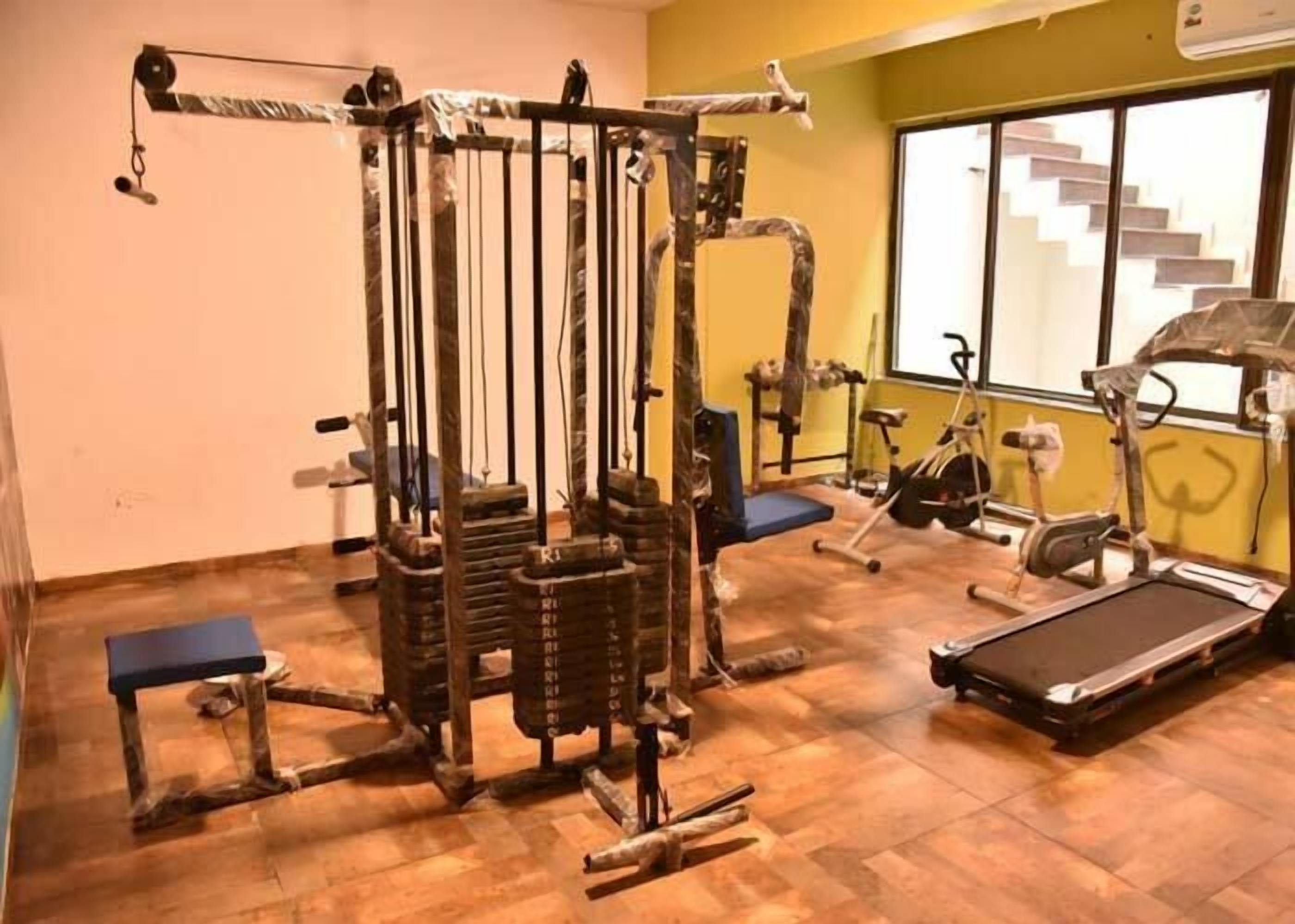 A gym with a cable machine, a bench, and a treadmill.