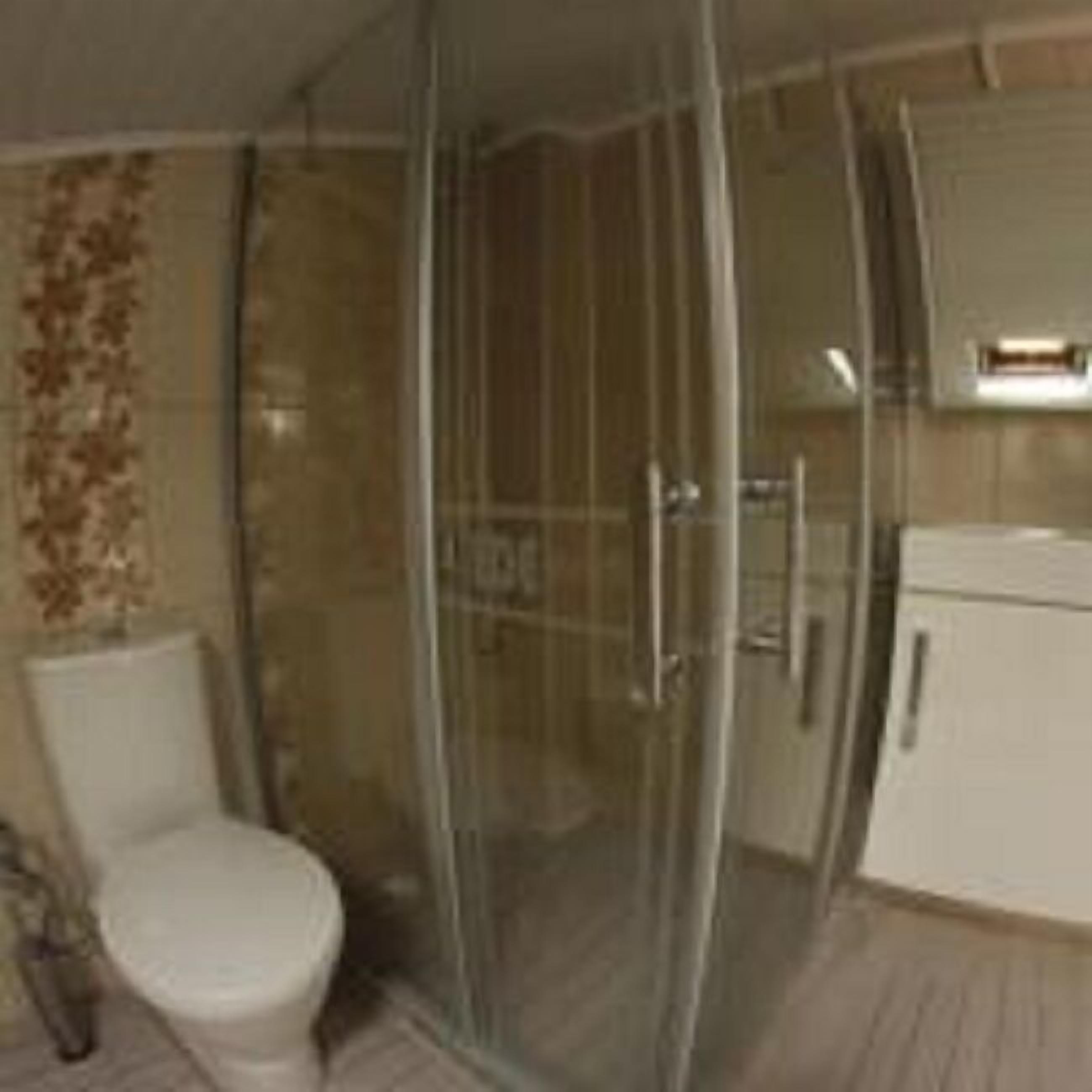 A bathroom with a glass shower enclosure, a toilet, and a sink.