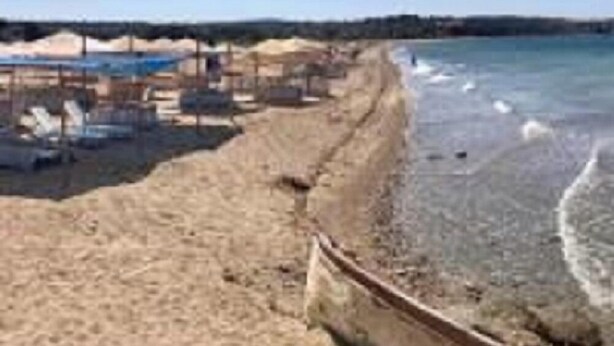 A beach with a sandy shore, a small boat, and a clear blue sky. - Ede Apart Hotel (Ezine)