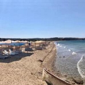 A beach with a sandy shore, a small boat, and a clear blue sky. - Ede Apart Hotel (Ezine)