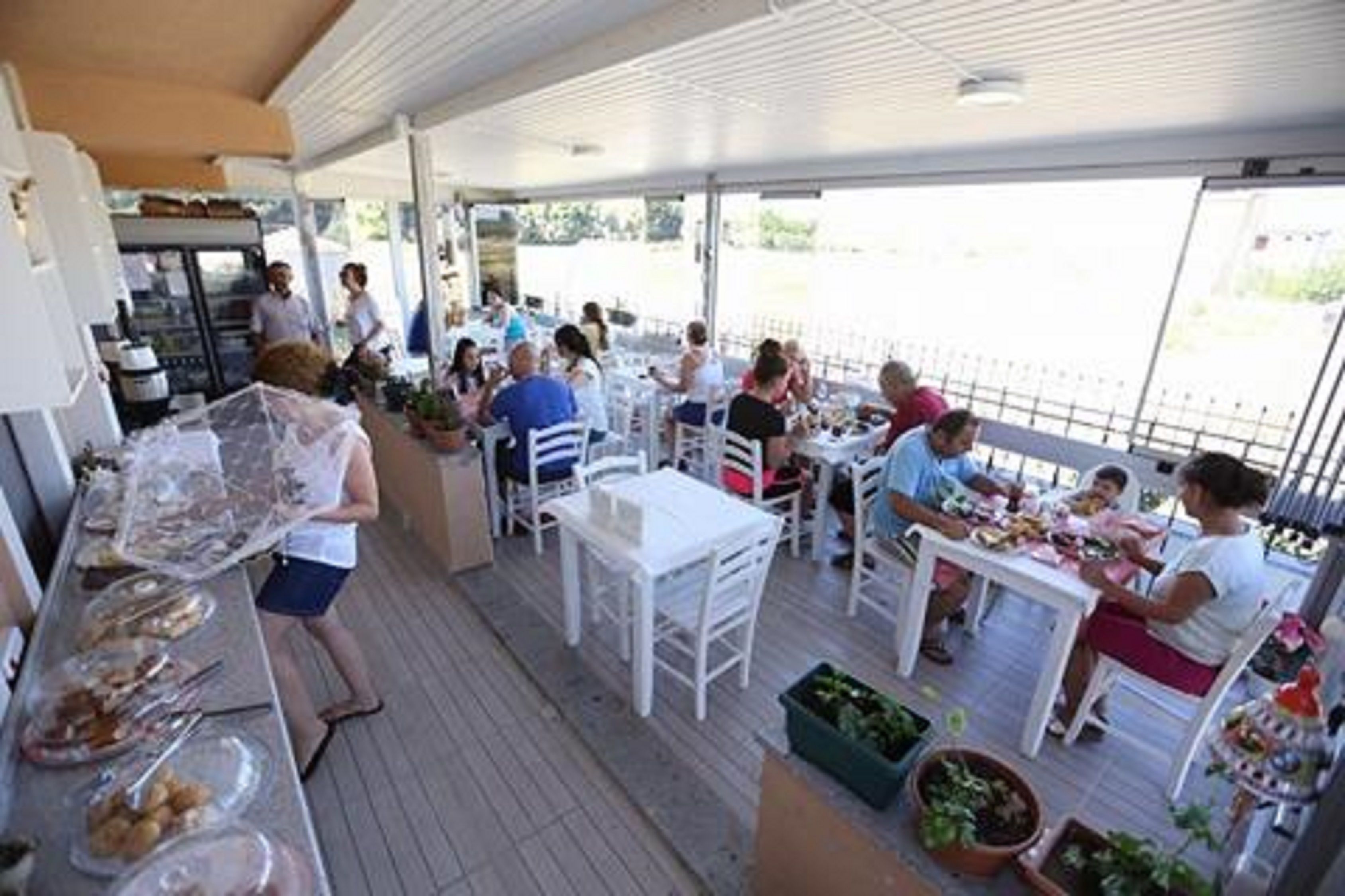 Een buiteneetgedeelte met tafels en stoelen, een buffet met eten, en uitzicht op de omgeving.