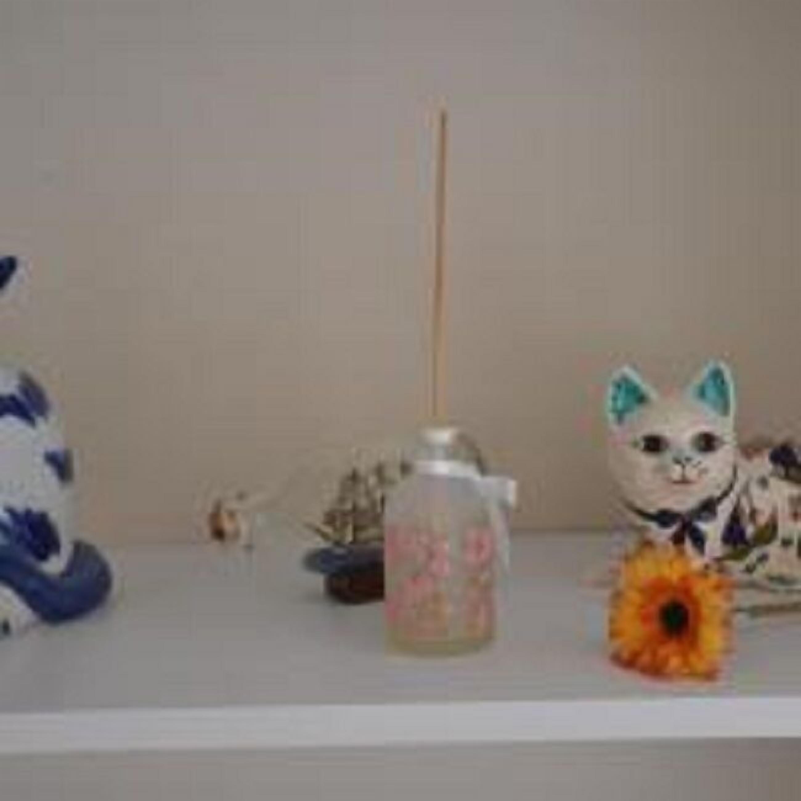 A shelf with a decorative cat figurine, a small bottle, and a sunflower.